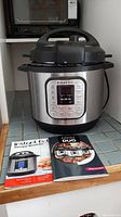 Front view of Instant Pot IP-DUO on counter with two recipe booklets in front.