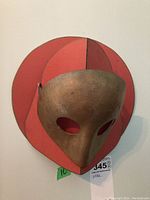 Front view of gold mask mounted on red holder
