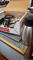 Overview photo of Santos coffee set components inside a Bodum box including burner, glass carafe, and glass dome cover, with Cresimo water carafe on the side.
