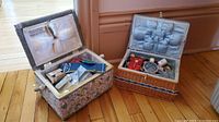 Photo showing two sewing baskets open, displaying assorted sewing supplies inside.