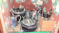 Overview of multiple silver plated items including water jug, coffee pot, gravy boat, crystal coasters in ornate holder.