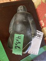 View from top showing abstract human face and body form in dark stone with dimensions label.