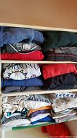 Stacked folded vintage sweatshirts and T-shirts in a drawer, showing various colors and prints including San Francisco graphic.