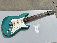 Full body view of teal electric guitar showing body, pickguard, pickups, and part of neck