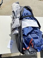 Blue and gray family dome tent packed inside a black carrying bag showing product instruction sheet attached to bag.