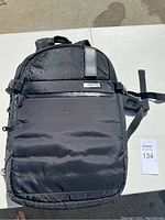 Full front view of a black Duchamp backpack with leather detail and metal branding plate on front pocket.