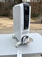 Left side view of the DeLonghi white oil-filled space heater showing digital control panel and wheels.
