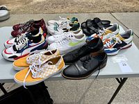 Wide shot of all 7 pairs of shoes on a table outdoors showing various styles and colors.