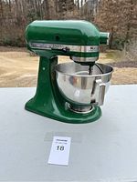 Green KitchenAid stand mixer with stainless steel bowl, shown from the side.