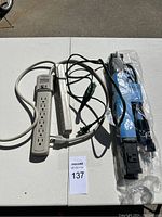 Three power strips shown on table, one beige, one white, one blue in packaging