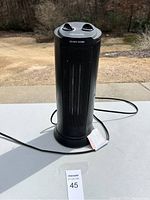 Front and top view of the black Pelonis cylindrical space heater showing front grille, control knobs, and power cord.