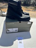 Side view of black Timberland boots on top of original box outdoors.
