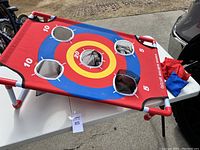 Photo showing GoSports Bullseye Bounce rectangular target with five scoring holes in red, blue, yellow, on white PVC frame, and both red and blue bean bags.
