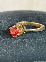 Angled front view showing red faceted stone in six-prong setting