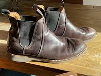 Photo showing the outer side and top view of both brown leather Chelsea boots with elastic gore panels and heel pull tabs.