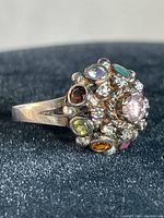 Close-up photo of vintage sterling silver ring showing multiple colored stones clustered on top with a decorative silver band