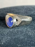 Close-up showing the front of the ring, blue iridescent stone and triangular cutout detail