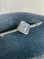 Close-up of the square blue stone on the sterling silver pin, showing stone color and setting details.