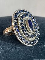 Close-up of the ring front showing the blue stones and detailed metal work.