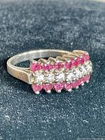 Close-up of the ring showing three rows of stones with pink, purple, and clear stones on a silver band.