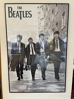 Front view of vintage The Beatles framed poster, black and white image of band walking on city street.