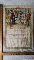 Full front view of certificate on patterned surface with wooden rulers showing scale