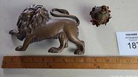 Photo showing the brass lion figurine and brass curtain weight with a ruler for scale