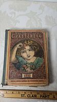 Front cover of 'Chatterbox' children's book dated 1880, showing an illustrated young girl holding a flower with some age wear.
