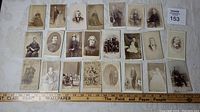Wide view of 25 antique photo cards laid out on a white textured surface with a measuring ruler showing scale.