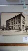 Photo of vintage black and white historic building with distant horse-drawn ambulance