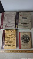 Photo showing front and back covers of two vintage phonebooks with advertisements for local businesses including Modern Taxi and Jas Swift & Co Coal.