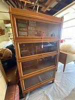 Front view of the assembled 4-tier oak wood and glass barrister bookcase in garage.