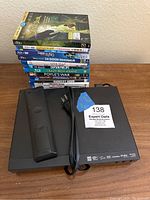 Photo showing Blu-Ray player, remote, power cord, and stack of 12 Blu-Ray movie cases including The Jungle Book, Sing, The Good Dinosaur, Captain Phillips, Crazy Rich Asians, and more.