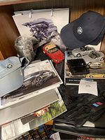Photo of BMW branded bag, caps, brochures, model cars, gloves, and mug