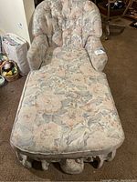 Front view of padded floral cloth chaise lounge with ruffled bottom skirt showing cushioned seat and backrest.