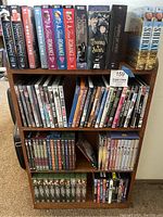 Photo showing the full wooden storage unit with multiple shelves holding DVDs and VHS tapes in upright position.