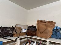 Wide angle view of seven assorted leather purses and handbags arranged on a shelf corner, showing variety of sizes and colors.