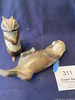 Photo showing the chipmunk standing and the otter lying on its back on a blue cloth background.