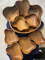 Top-down photo showing large salad bowl with eight smaller matching bowls nested inside along with the dark wood serving tray partially visible.