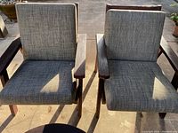 Top-down view of two patio chairs with woven gray plastic cushions and wooden frames.