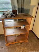 Front and angled view of the knotted pine bookshelf showing three shelves, natural wood grain and knots, and decorative base.