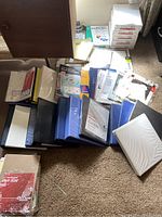 Photo showing numerous reams of copy paper, specialty paper packs and several opened and packed binders laid out