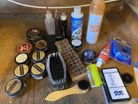 Overview of shoe polishing accessories including tins of cream and polish, brushes, and cleaning liquids.