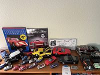 Wide view of the toy car collection including small and medium diecast car models, books and Route 66 sign.
