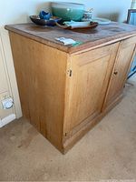 Side view of antique pine jam cupboard showing two doors and wood finish with wear.