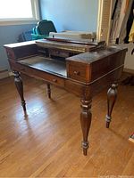 Full front angle view of antique wooden writing desk showing side drawers and enclosed top compartment, revealing storage pigeonholes and small drawers inside.