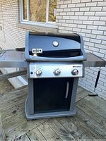Full front view of grill on wooden deck with side shelf extended
