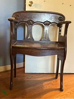 Front view of the carved wooden chair showing detailed backrest and armrests.