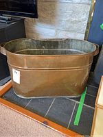 Front and side view showing the copper tub's shape, size, and external condition with dents and patina.