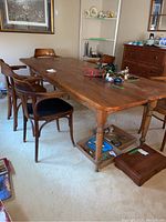 Full view of pine harvest table with five chairs arranged around it, tabletop items removed to show set.